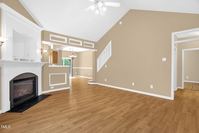 7807 Braefield Dr, Raleigh, NC 27616 - unfurnished living room featuring ceiling fan, high vaulted ceiling, a chandelier, light wood-style floors, and a glass covered fireplace
