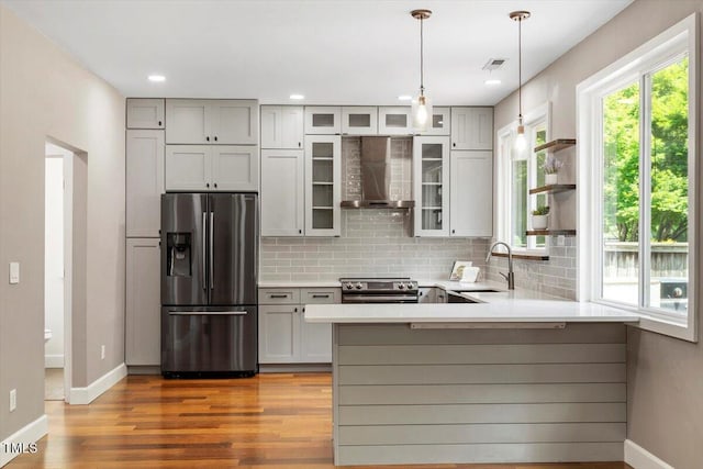 7414 Brandon Allen Ave, Raleigh, NC 27613 - kitchen with appliances with stainless steel finishes, wall chimney exhaust hood, decorative backsplash, a peninsula, and light countertops