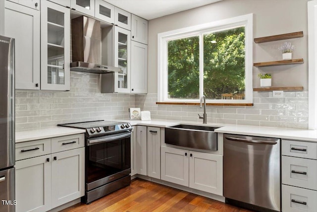 7414 Brandon Allen Ave, Raleigh, NC 27613 - kitchen with appliances with stainless steel finishes, wall chimney range hood, light countertops, backsplash, and wood finished floors
