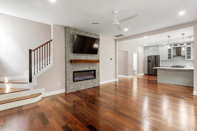 7414 Brandon Allen Ave, Raleigh, NC 27613 - unfurnished living room with a ceiling fan, dark wood-style floors, stairs, recessed lighting, and a large fireplace