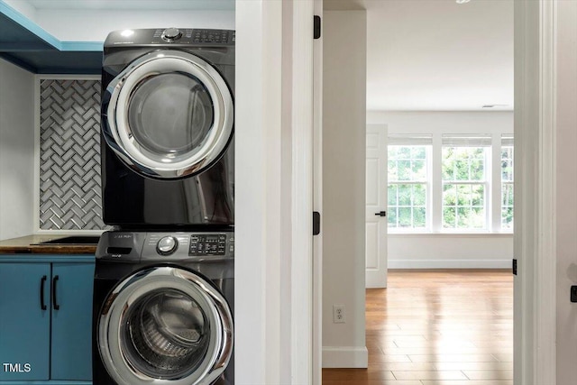 7414 Brandon Allen Ave, Raleigh, NC 27613 - washroom with stacked washer and clothes dryer, cabinet space, and wood finished floors