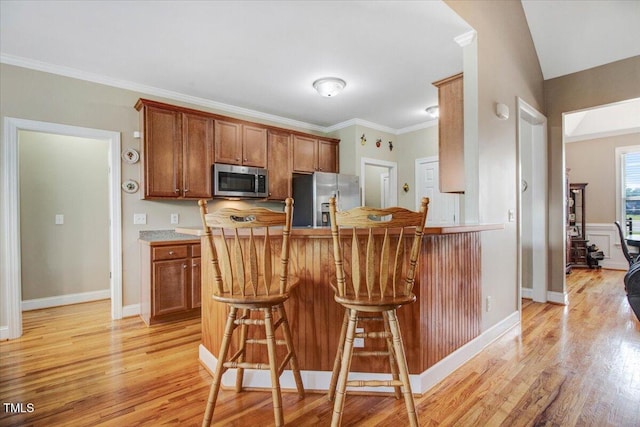 8101 Claybrooke Ct, Willow Springs, NC 27592 - kitchen featuring appliances with stainless steel finishes, brown cabinetry, a breakfast bar area, light wood-type flooring, and ornamental molding