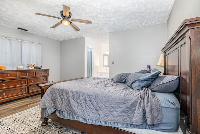 2205 Indigo Bush Pl, Fayetteville, NC 28304 - bedroom with wood finished floors, a textured ceiling, ceiling fan, and ensuite bathroom