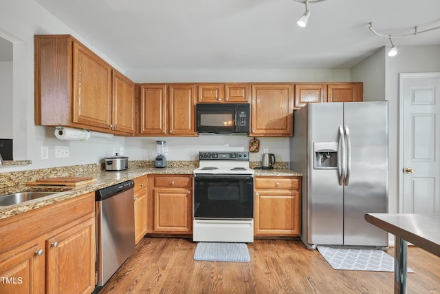 8532 Swarthmore Dr, Raleigh, NC 27615 - kitchen featuring appliances with stainless steel finishes, light wood-type flooring, light stone countertops, and brown cabinets