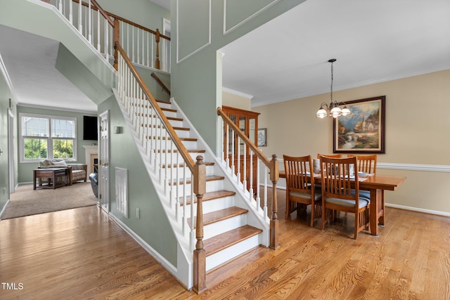 2104 Brockfield Ct, Raleigh, NC 27614 - staircase with wood finished floors, crown molding, a fireplace, and a chandelier