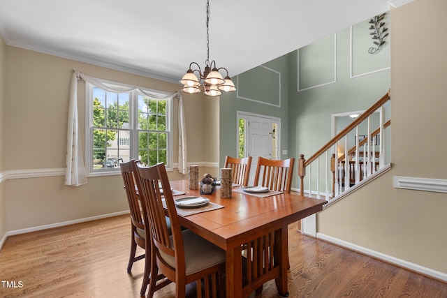 2104 Brockfield Ct, Raleigh, NC 27614 - dining room featuring a chandelier, wood finished floors, stairs, and ornamental molding