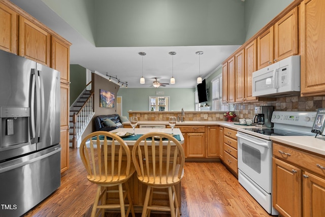 2104 Brockfield Ct, Raleigh, NC 27614 - kitchen with white appliances, tasteful backsplash, light wood finished floors, a peninsula, and ceiling fan