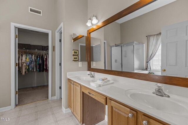 2104 Brockfield Ct, Raleigh, NC 27614 - bathroom featuring a shower stall, double vanity, a walk in closet, and tile patterned floors