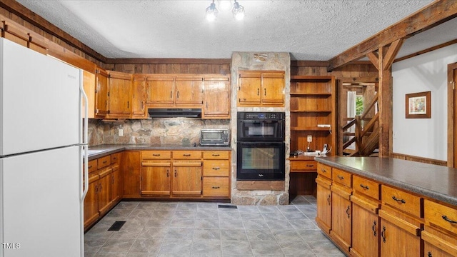 424 Roy Carver Rd, Semora, NC 27343 - kitchen with freestanding refrigerator, under cabinet range hood, a textured ceiling, brown cabinets, and dark countertops
