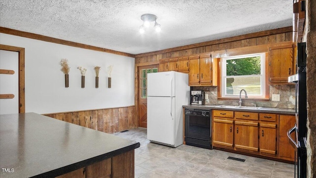 424 Roy Carver Rd, Semora, NC 27343 - kitchen with dishwasher, freestanding refrigerator, wooden walls, brown cabinets, and decorative backsplash