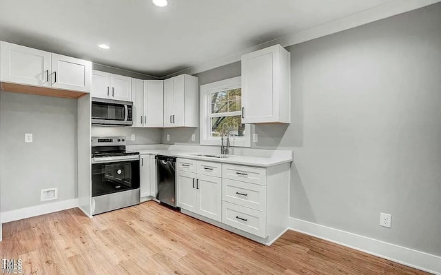 900 Woodrow St S, Wilson, NC 27893 - kitchen featuring appliances with stainless steel finishes, light countertops, white cabinets, light wood-style flooring, and recessed lighting