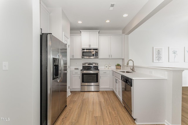 14309 Foxcroft Rd, Raleigh, NC 27614 - kitchen featuring appliances with stainless steel finishes, light wood-type flooring, light countertops, a peninsula, and recessed lighting