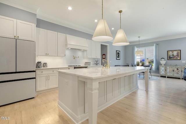 201 S Ennis St, Fuquay Varina, NC 27526 - kitchen featuring custom range hood, freestanding refrigerator, crown molding, white cabinets, and light wood finished floors