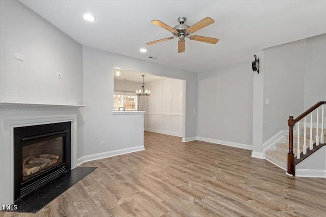 3021 Winding Waters Way, Raleigh, NC 27614 - unfurnished living room with wood finished floors, a ceiling fan, a glass covered fireplace, a chandelier, and recessed lighting
