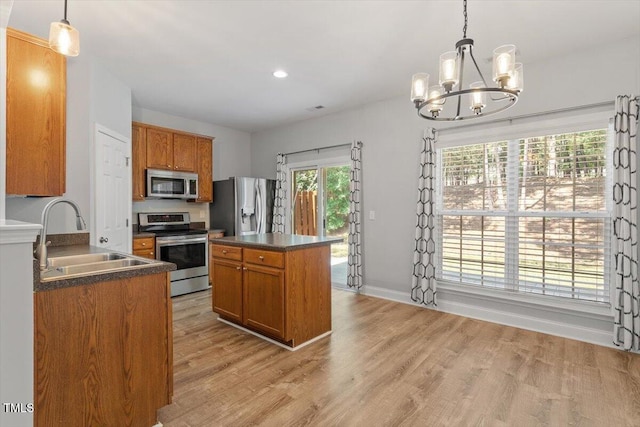 3021 Winding Waters Way, Raleigh, NC 27614 - kitchen featuring stainless steel appliances, dark countertops, a chandelier, light wood-style floors, and brown cabinetry