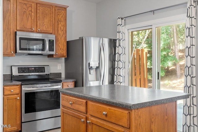 3021 Winding Waters Way, Raleigh, NC 27614 - kitchen with appliances with stainless steel finishes, dark countertops, brown cabinetry, and a kitchen island