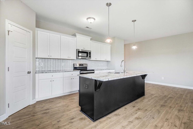 106 Fynloch Chase Dr, Fremont, NC 27830 - kitchen featuring stainless steel appliances, white cabinets, backsplash, and a center island with sink