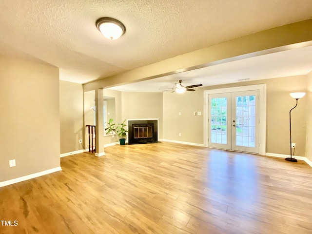 4324 Halliwell Dr, Raleigh, NC 27606 - unfurnished living room with light wood-style floors, a textured ceiling, ceiling fan, french doors, and a fireplace with flush hearth