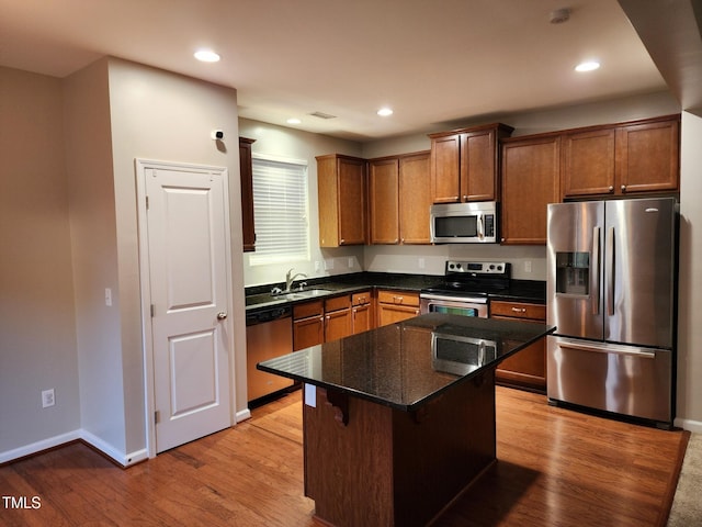 302 Glenview Ln, Durham, NC 27703 - kitchen with appliances with stainless steel finishes, light wood-style floors, recessed lighting, a center island, and dark stone counters