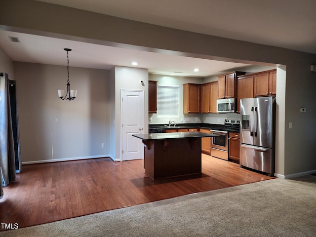 302 Glenview Ln, Durham, NC 27703 - kitchen featuring appliances with stainless steel finishes, dark countertops, a center island, a kitchen breakfast bar, and hanging light fixtures