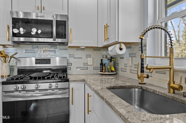1603 N Alston Ave, Durham, NC 27701 - kitchen featuring appliances with stainless steel finishes, white cabinets, decorative backsplash, and light stone counters