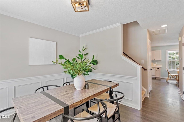 404 Ascott Way, Durham, NC 27713 - dining space featuring dark wood-type flooring, a wainscoted wall, ornamental molding, a textured ceiling, and a decorative wall
