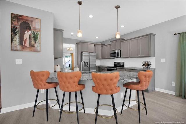 208 Walker Downs Cir, Fayetteville, NC 28305 - kitchen featuring appliances with stainless steel finishes, gray cabinetry, a breakfast bar, light wood-style flooring, and recessed lighting
