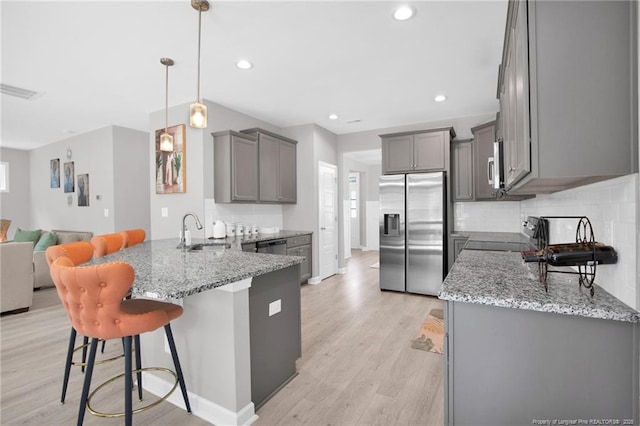 208 Walker Downs Cir, Fayetteville, NC 28305 - kitchen with appliances with stainless steel finishes, gray cabinetry, a peninsula, light stone counters, and open floor plan