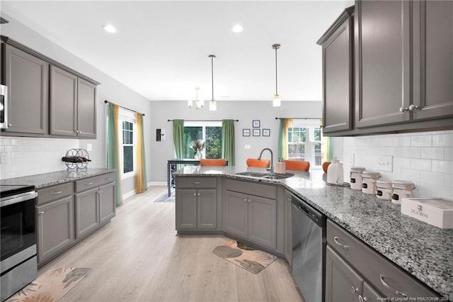 208 Walker Downs Cir, Fayetteville, NC 28305 - kitchen featuring stainless steel appliances, a peninsula, light wood-style flooring, decorative backsplash, and light stone counters