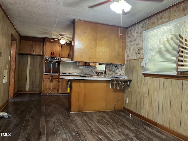 417 Sunnyview Rd, Henderson, NC 27536 - kitchen with black oven, a ceiling fan, brown cabinetry, a peninsula, and a textured ceiling