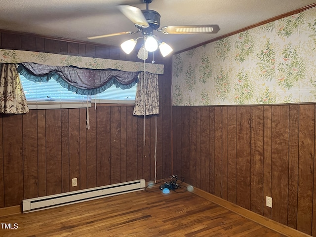 417 Sunnyview Rd, Henderson, NC 27536 - spare room with baseboard heating, wood finished floors, ceiling fan, wooden walls, and ornamental molding