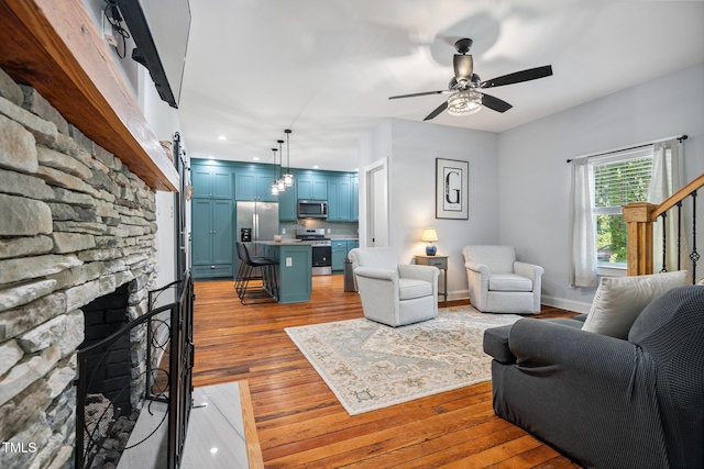 605 W Holt St, Mebane, NC 27302 - living area featuring light wood-type flooring, a stone fireplace, recessed lighting, and ceiling fan
