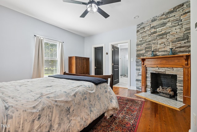 605 W Holt St, Mebane, NC 27302 - bedroom with dark wood-style flooring, a stone fireplace, and ceiling fan