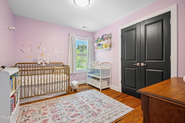 605 W Holt St, Mebane, NC 27302 - bedroom with wood finished floors, a nursery area, a closet, and a chandelier
