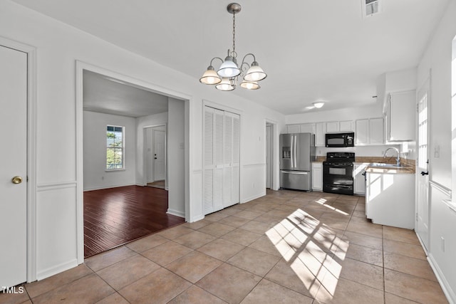 7 Hannah Ct, Durham, NC 27713 - kitchen with black appliances, a chandelier, white cabinetry, pendant lighting, and light tile patterned flooring