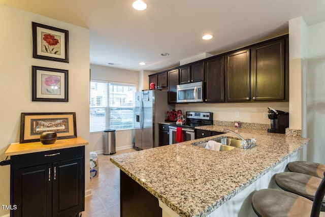 4009 Tresco Xing, Raleigh, NC 27616 - kitchen featuring stainless steel appliances, light stone counters, a kitchen breakfast bar, recessed lighting, and a peninsula