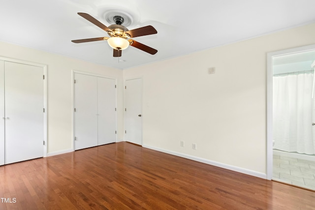 6608 Quiet Cove Ct, Raleigh, NC 27612 - unfurnished bedroom featuring two closets, wood finished floors, ensuite bathroom, and a ceiling fan