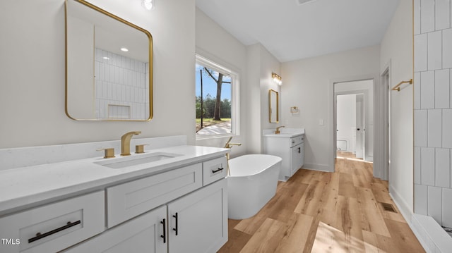 5027 Preacher Holmes Rd, Graham, NC 27253 - full bathroom with two vanities, a freestanding bath, wood finished floors, and a shower