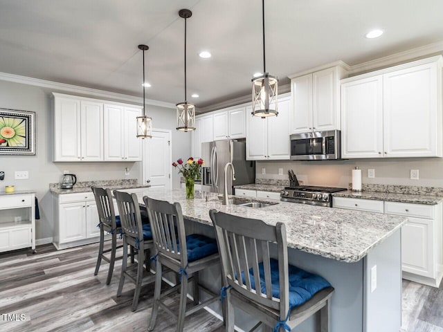 3441 Jordan Shires Dr, New Hill, NC 27562 - kitchen featuring stainless steel appliances, crown molding, wood finished floors, a center island with sink, and white cabinets