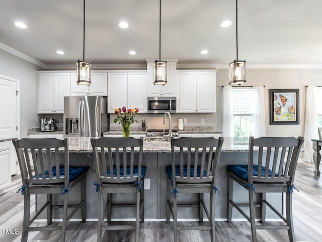 3441 Jordan Shires Dr, New Hill, NC 27562 - kitchen featuring appliances with stainless steel finishes, crown molding, light wood-style floors, white cabinets, and a spacious island
