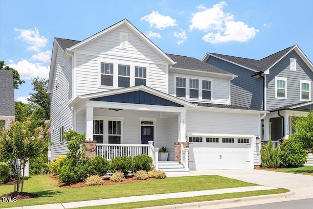 223 Chauncey Cir, Chapel Hill, NC 27516 - view of front facade with covered porch, a garage, concrete driveway, a front yard, and board and batten siding