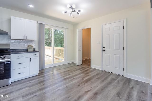400 Minchew St SE, Wilson, NC 27893 - kitchen with stainless steel electric range, white cabinetry, light wood-style floors, dark countertops, and decorative backsplash