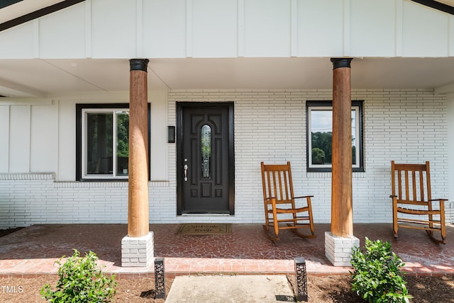 6005 Lake Wheeler Rd, Raleigh, NC 27603 - view of exterior entry with board and batten siding, a porch, and brick siding