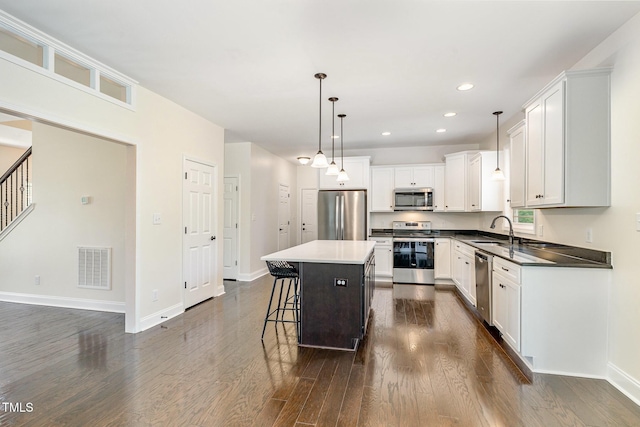 407 Kadir Womble Dr, New Hill, NC 27562 - kitchen featuring stainless steel appliances, dark wood finished floors, a breakfast bar, a kitchen island, and white cabinets