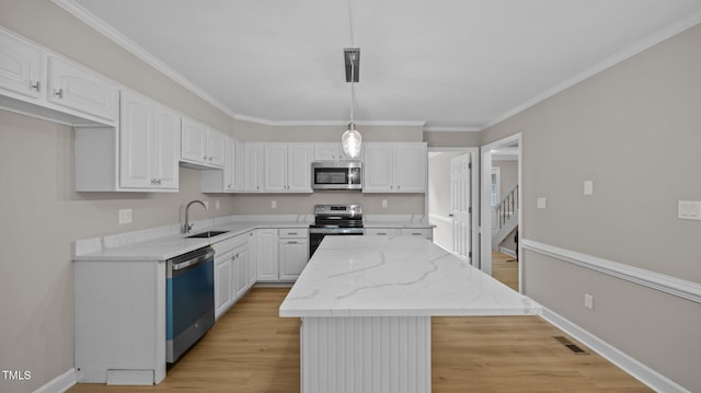 1524 Wedgewood Dr, Graham, NC 27253 - kitchen featuring appliances with stainless steel finishes, a kitchen island, white cabinets, light wood-style flooring, and light stone counters