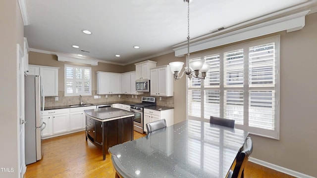 112 Salmon River Dr, Durham, NC 27705 - kitchen featuring appliances with stainless steel finishes, a center island, crown molding, backsplash, and a chandelier