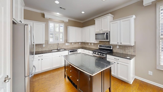 112 Salmon River Dr, Durham, NC 27705 - kitchen with appliances with stainless steel finishes, light wood-style flooring, decorative backsplash, white cabinetry, and crown molding
