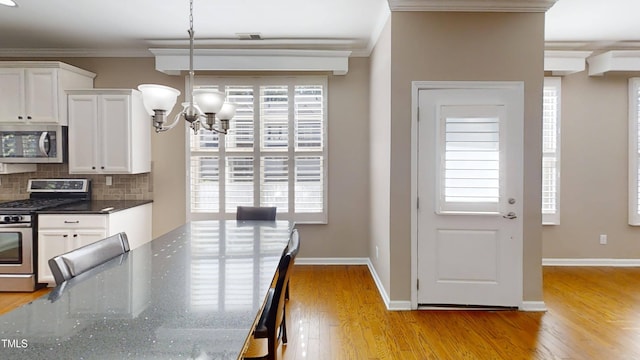 112 Salmon River Dr, Durham, NC 27705 - dining area featuring a chandelier, crown molding, light wood-type flooring, and plenty of natural light