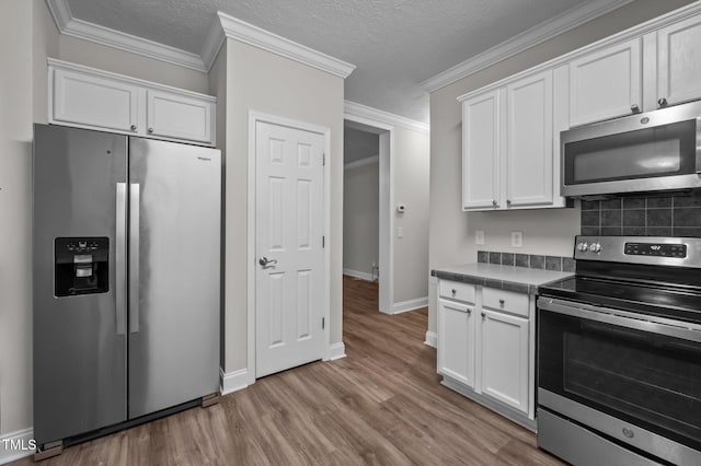 116 Justice St, Chapel Hill, NC 27516 - kitchen featuring stainless steel appliances, white cabinets, wood finished floors, backsplash, and crown molding