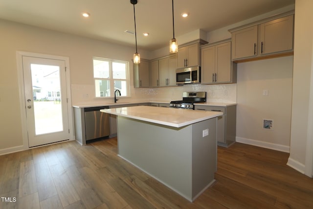 1218 Tredenham Way, Durham, NC 27703 - kitchen with appliances with stainless steel finishes, gray cabinetry, backsplash, a kitchen island, and light countertops